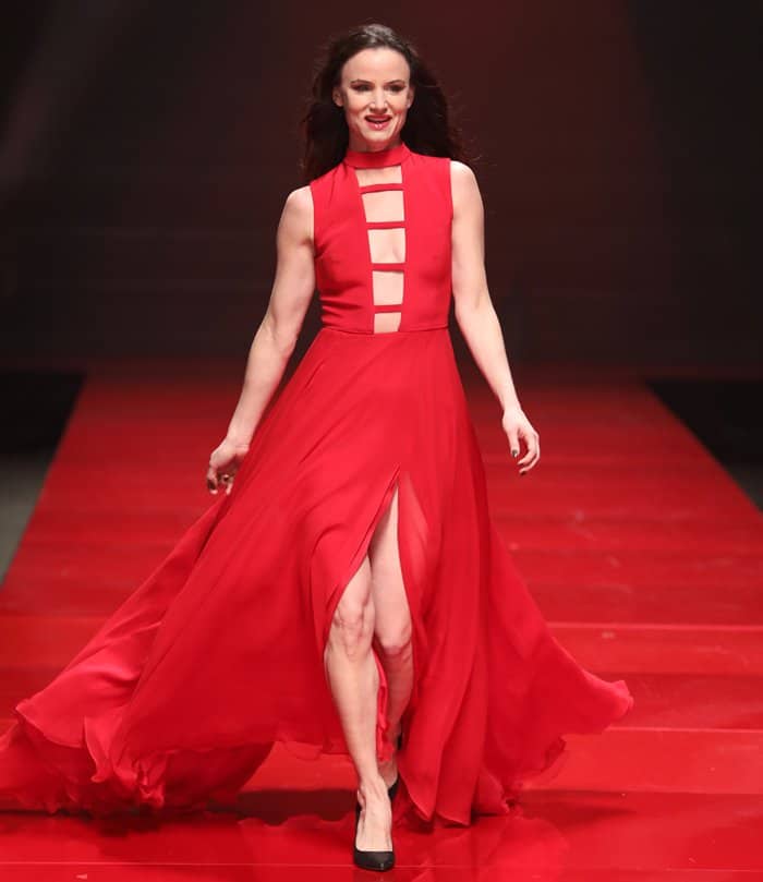 Juliette Lewis pairs her daring red gown, featuring bold cutouts and a high slit, with classic black pointed-toe heels for an effortlessly chic look