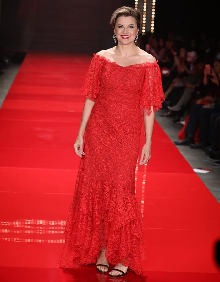 Lucy Lawless exudes elegance in an off-shoulder red lace gown with flowing details, paired perfectly with classic black strappy heels, as she walks the runway at the 'Go Red for Women' fashion show at the Hammerstein Ballroom in New York on February 9, 2017