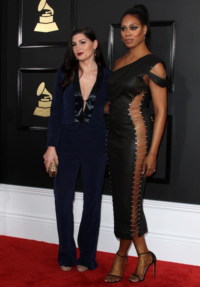 Laverne Cox stuns in a custom Bryan Hearns leather dress with jeweled chain links, while Trace Lysette radiates elegance in a sleek Jovani Signature suit at the 59th Annual GRAMMY Awards