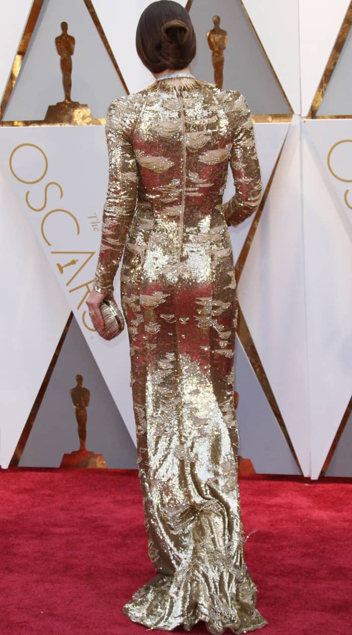Jessica Biel’s KaufmanFranco gown features intricate silver sequins and a dramatic train, perfectly complemented by her sleek, sculptural updo that highlights the dress’s elegant open-back zipper detail