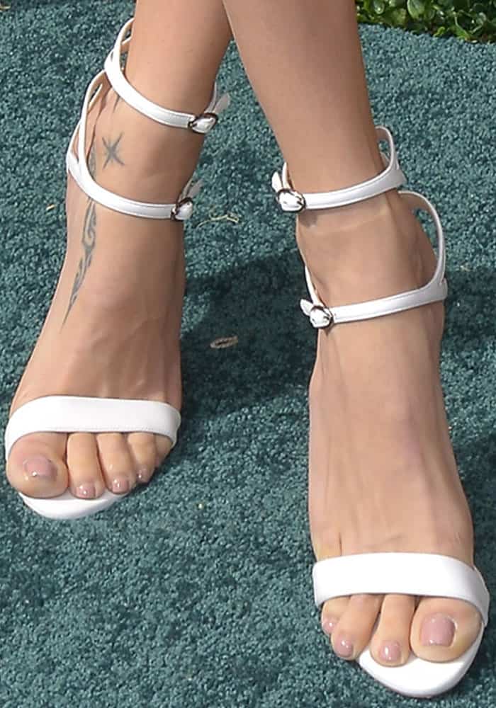 Adriana Lima flaunts a chic pedicure while stepping out in white strappy sandals, though her toes slightly overhang the edges
