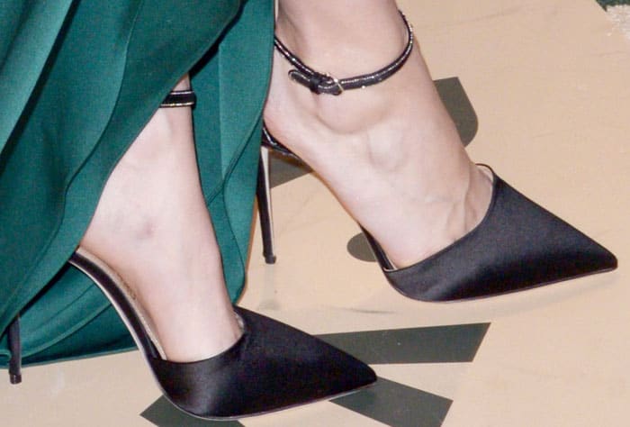 Brie Larson completes her look with elegant black satin ankle-strap pumps by Salvatore Ferragamo
