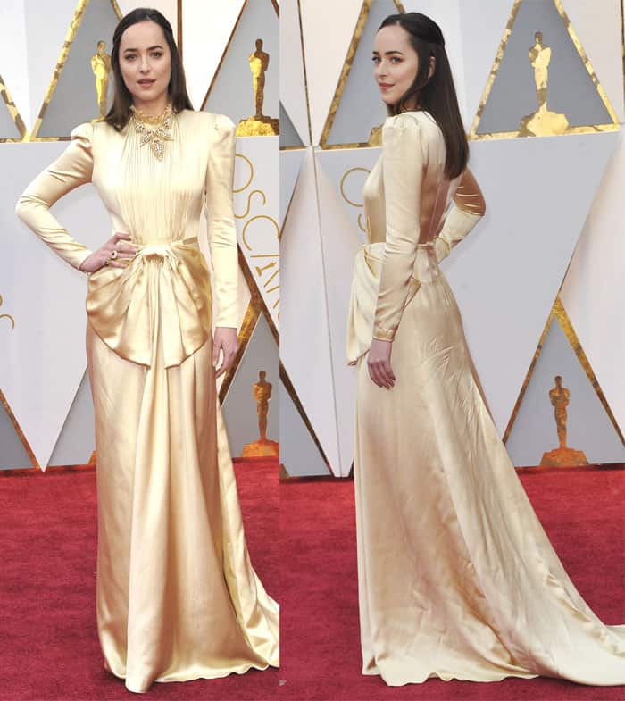 Dakota Johnson channels vintage Hollywood glamour in a satin gold Gucci gown featuring a high neckline, dramatic bow detail, and a flowing silhouette