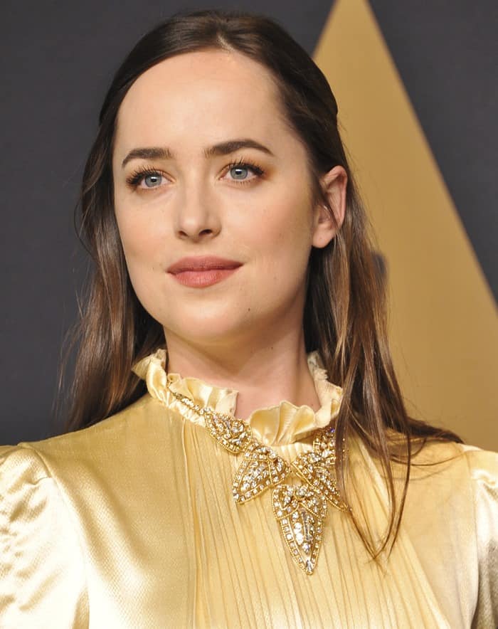 Dakota Johnson complemented her golden Gucci gown with sleek center-parted hair and soft, natural makeup, emphasizing her radiant elegance