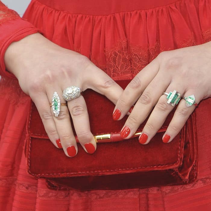 Ginnifer Goodwin paired her red velvet clutch with bold statement rings featuring intricate emerald and diamond details, perfectly complementing her vibrant red manicure