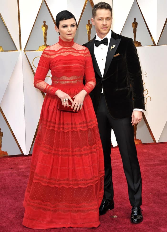 Ginnifer Goodwin radiated elegance in her red Zuhair Murad gown, while her husband Josh Dallas complemented her perfectly in a classic tuxedo with a chocolate velvet jacket, making them one of the most striking couples on the Oscars red carpet
