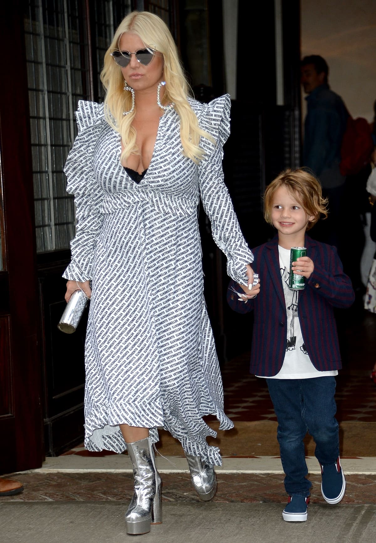 On May 10, 2018, in New York City, Jessica Simpson, joined by Ace Knute Johnson, showcased a bold and eclectic fashion statement in a Vetements ruffled printed jersey dress, paired with metallic textured-leather platform ankle boots by Vetements, Saint Laurent Lou Lou heart sunglasses in silver, and Saint Laurent XL smoking oval drop crystal earrings