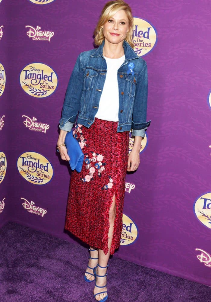 Julie Bowen exudes effortless style at the Tangled: Before Ever After screening, pairing a red woven floral skirt with a casual white tee, denim jacket, and striking blue Stuart Weitzman sandals