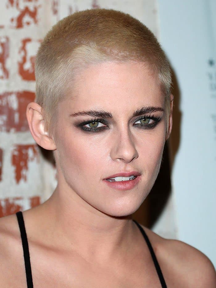 Kristen Stewart flaunts her bold blonde buzz cut and smoky eye makeup, enhancing her striking green eyes and exuding confidence