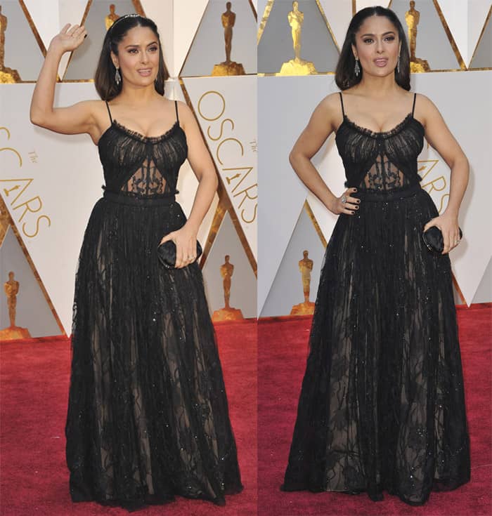 Salma Hayek exudes regal charm in a sheer black Alexander McQueen gown featuring intricate lace detailing and a flowing skirt, perfectly balancing elegance and allure