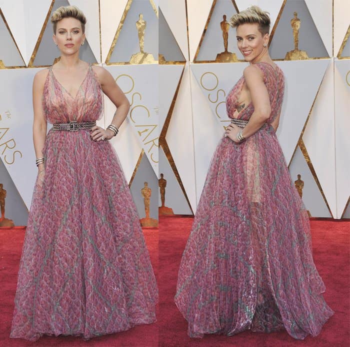 Scarlett Johansson combines edgy sophistication with feminine charm in a sheer pink Alaïa gown, featuring an intricate pattern and cinched with a metallic belt for a bold statement