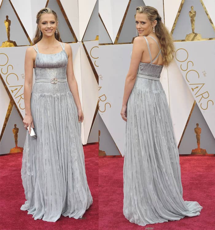 Teresa Palmer glows in a shimmering silver Prada gown, featuring a pleated skirt and delicate embellishments, perfectly complementing her radiant post-baby elegance