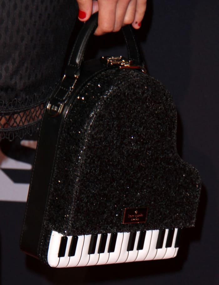 Asia Monet Ray carrying a black piano bag from Kate Spade