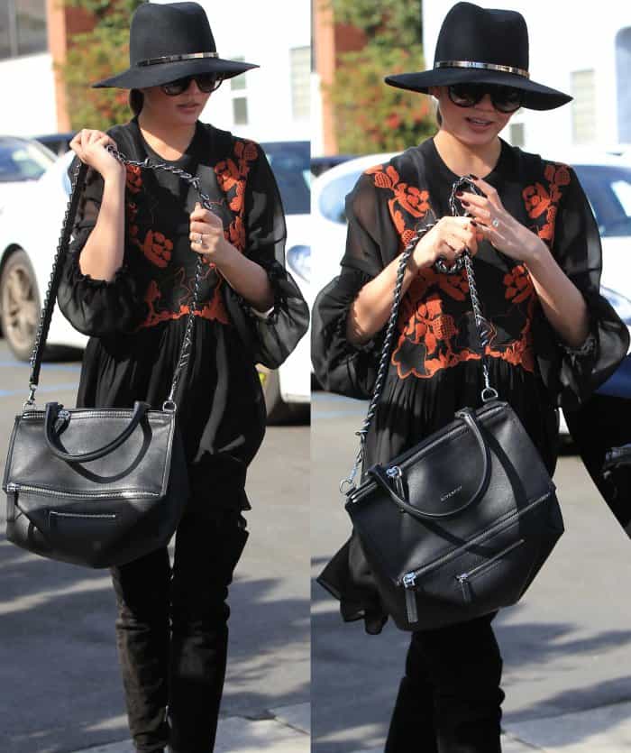 Chrissy Teigen effortlessly elevates her casual look with a black embroidered mini dress, oversized sunglasses, a wide-brim hat, and a sleek Givenchy bag during her outing in Beverly Hills