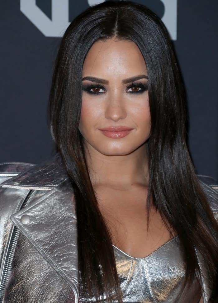 Demi Lovato’s sleek, straight hairstyle and smoky eye makeup with glossy nude lips added an edgy yet glamorous touch to her metallic look