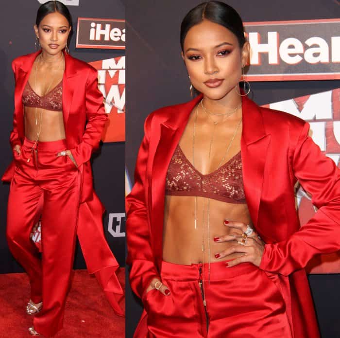 Karrueche Tran accessorized her red satin suit with layered gold necklaces, statement rings, delicate drop earrings, and a bold red manicure