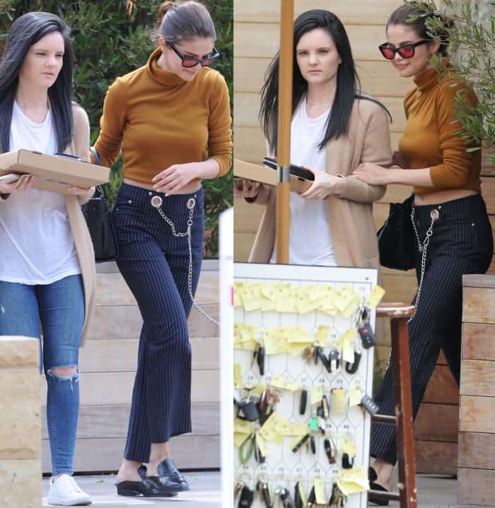 Selena Gomez is picking up pizza while wearing eye-catching Miaou pinstripe jeans featuring grommeted belt loops and silver chain detailing that add a playful, edgy twist to her chic, cropped ensemble