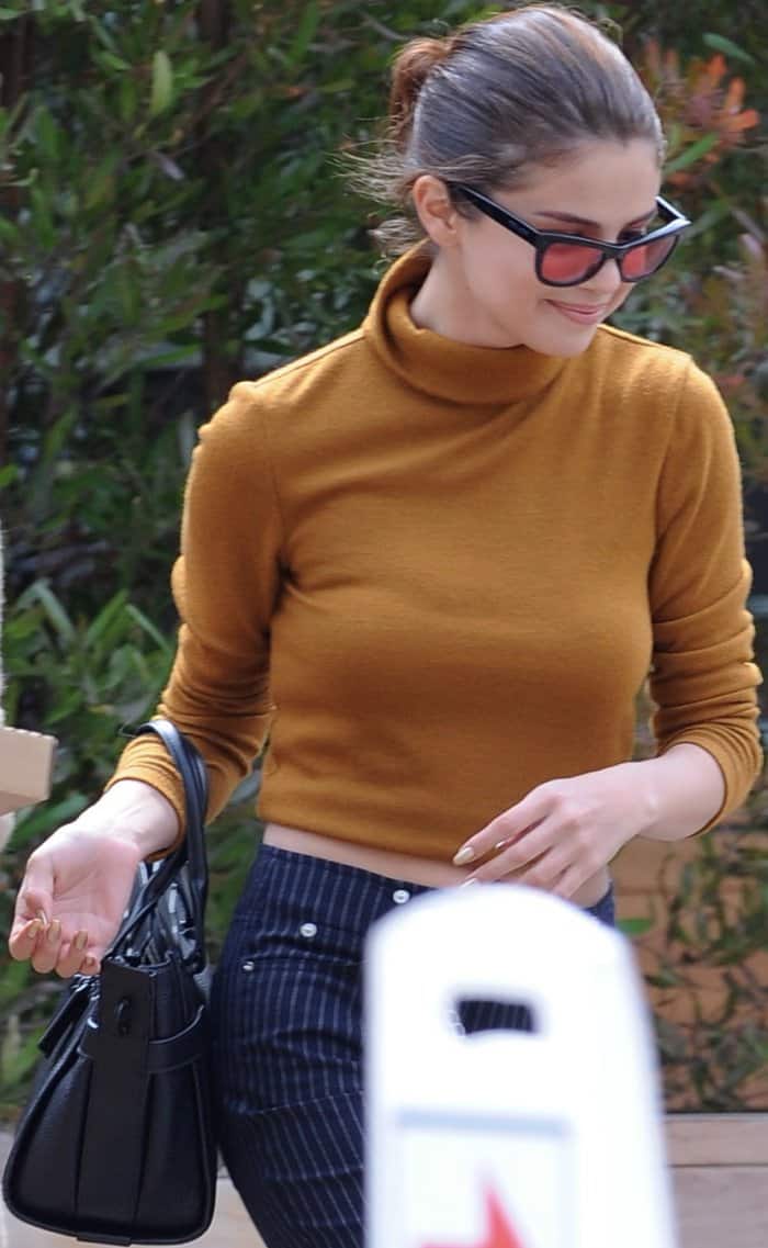 Selena Gomez wearing a Wayf fold-over turtleneck, Miaou "Tommy" pinstripe jeans, and Robert Clergerie "Alice" mules while out and about in Malibu