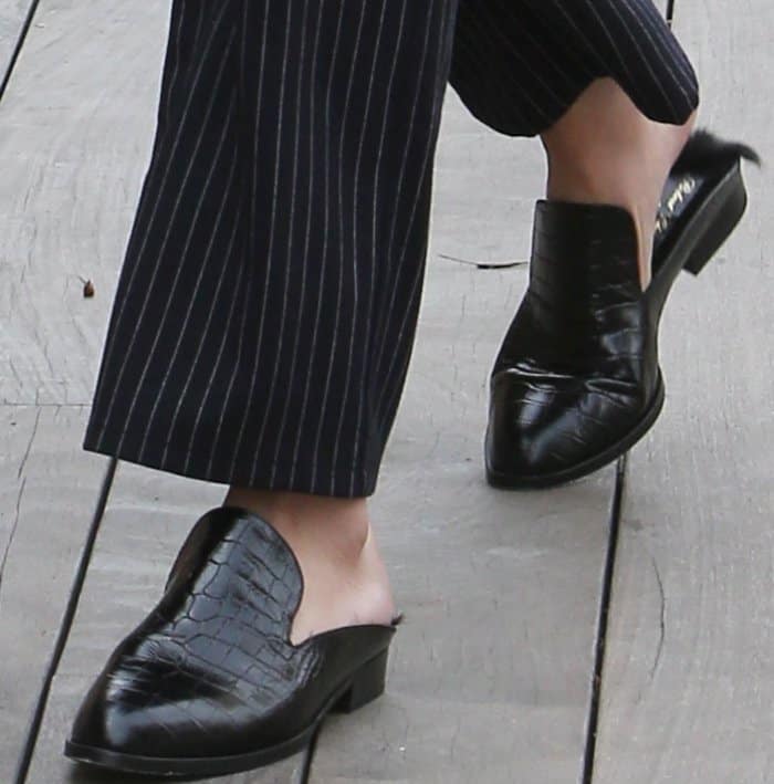 Selena Gomez completed her look with black Robert Clergerie “Alice” mules, featuring crocodile-embossed leather and a sleek, backless silhouette that blends structure with modern ease