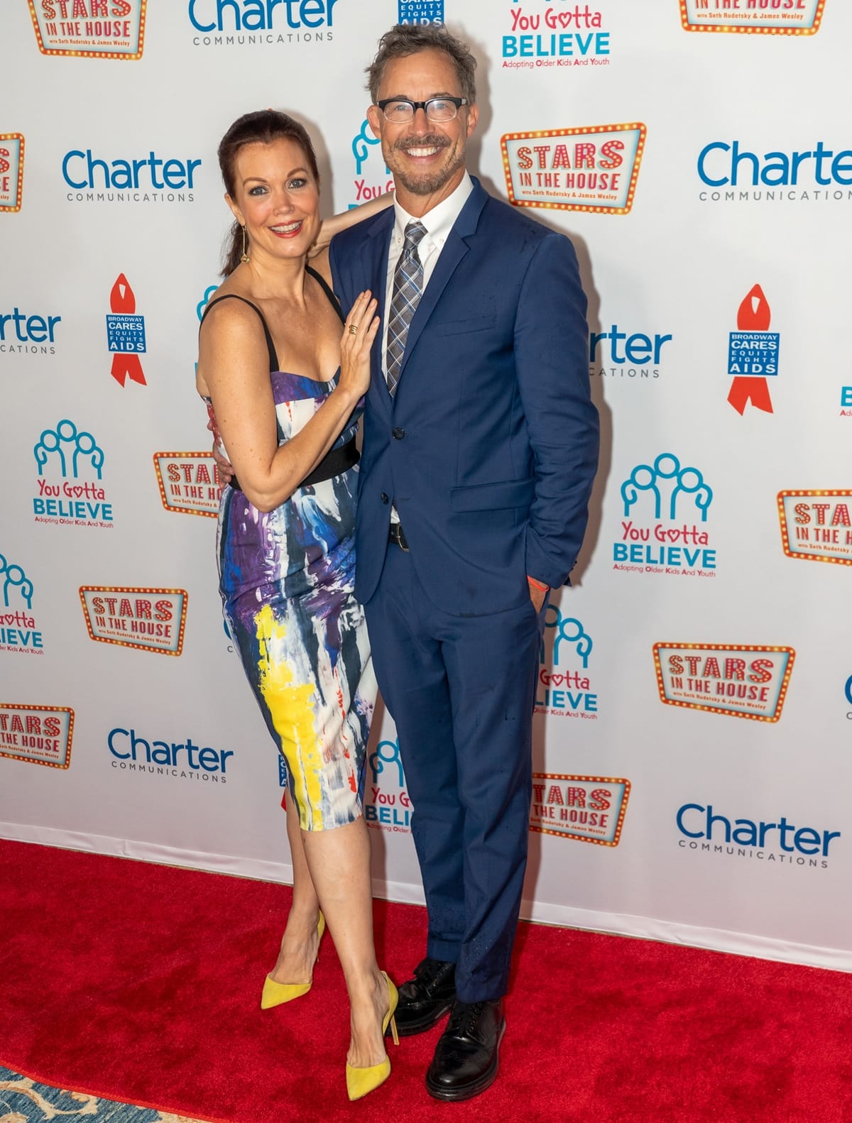 Bellamy Young pairs vibrant yellow pointed-toe heels with a painterly sheath dress, while Tom Cavanagh keeps it classic in a navy suit and patterned tie at the Stars in the House Benefit