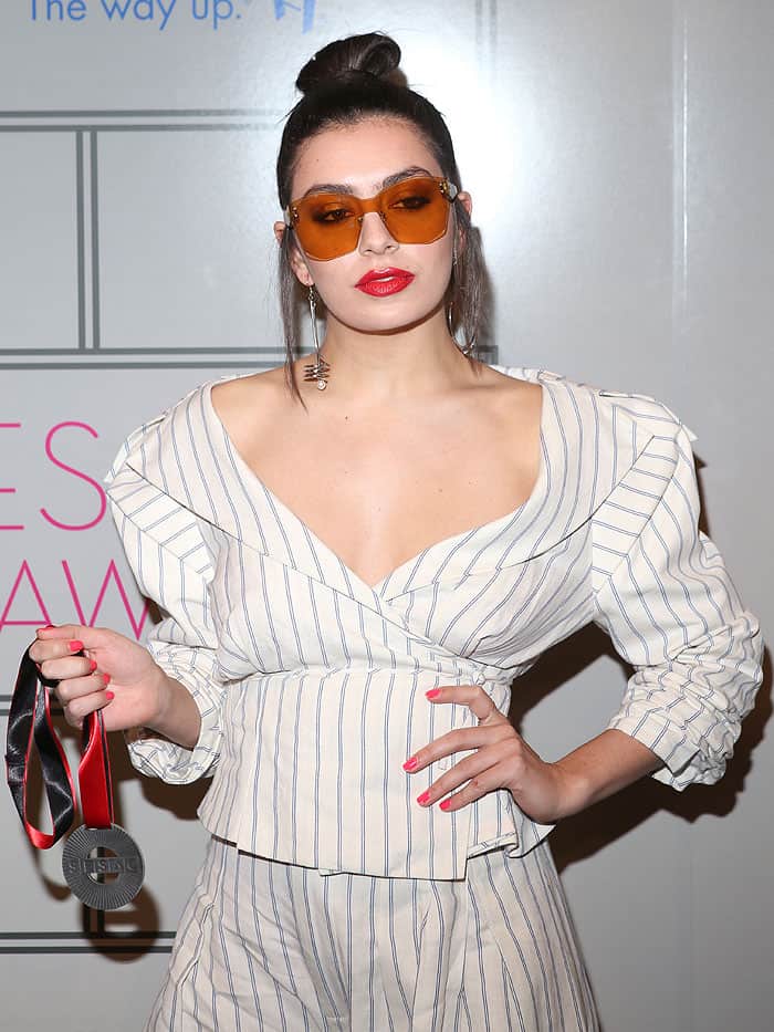 Charli XCX wore a pinstriped pajama set with burnt orange sunglasses and mismatched dangling earrings