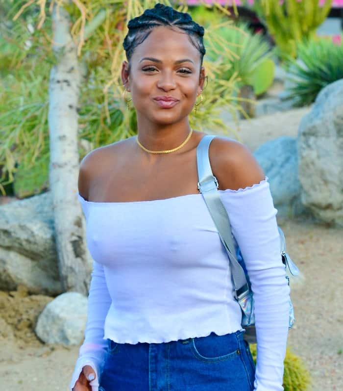 Christina Milian wore her hair in sleek braided buns and accessorized with gold hoop earrings and a delicate gold choker necklace, adding a chic finish to her off-shoulder festival look