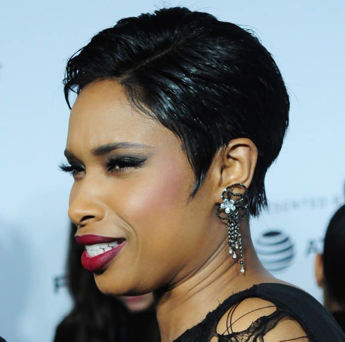 Jennifer Hudson reacts playfully on the red carpet, showing off her intricate, dangling Jacob & Co. earrings that perfectly complement her edgy style