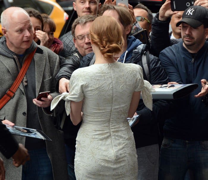 Jessica Chastain graciously stops to sign autographs for fans, giving a glimpse of the elegant lace detailing and bow-accented sleeves on the back of her Carolina Herrera dress