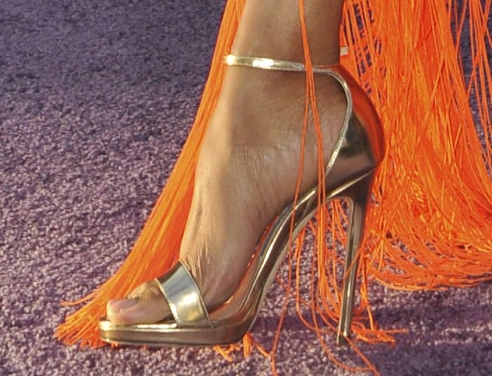 Zoe Saldaña's metallic Jimmy Choo sandals peek through the vibrant orange fringe of her Emilio Pucci gown