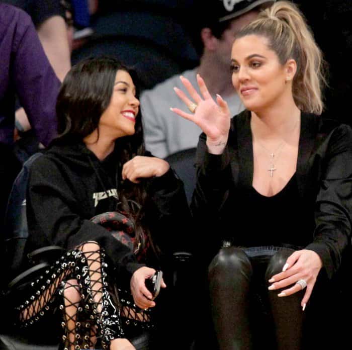 Kourtney Kardashian wearing Yeezy sandals and Khloé Kardashian wearing black pointy-toe pumps at Lakers vs. Cavaliers basketball game