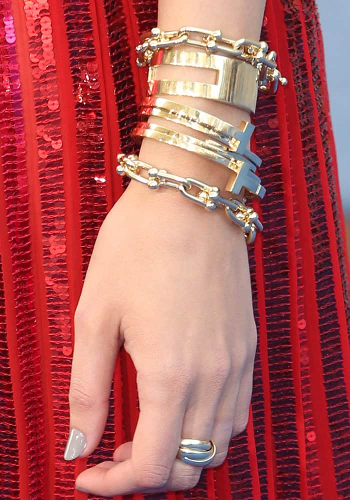 Gal Gadot completes her look with stacked gold Tiffany & Co. bracelets, a sculptural ring, and a glossy neutral manicure that adds subtle elegance