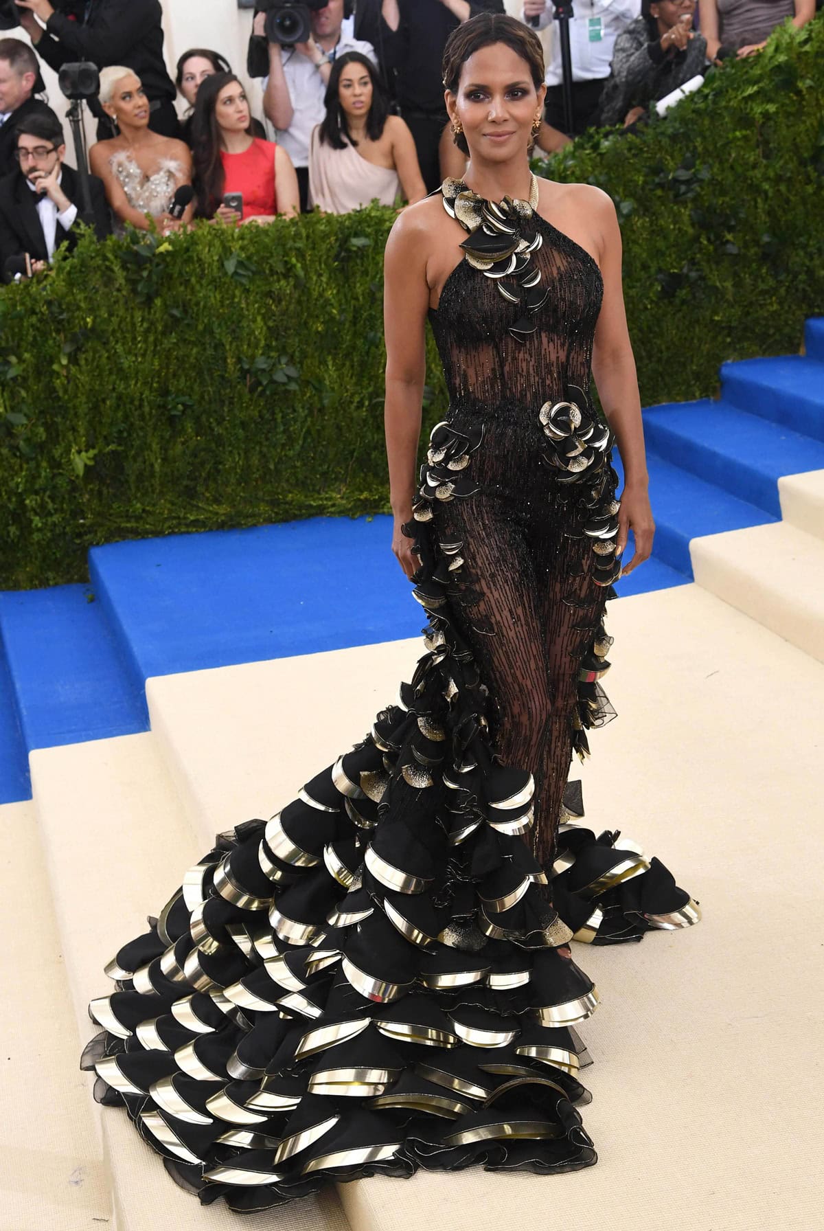 Halle Berry made a striking Met Gala debut in a sheer, floral-embellished Atelier Versace jumpsuit with a sculptural gold-trimmed train that captured the avant-garde spirit of the 2017 theme