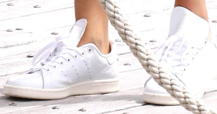 Kendall Jenner pairs her boating look with classic white Adidas 'Stan Smith' sneakers, adding a sporty touch to her chic ensemble