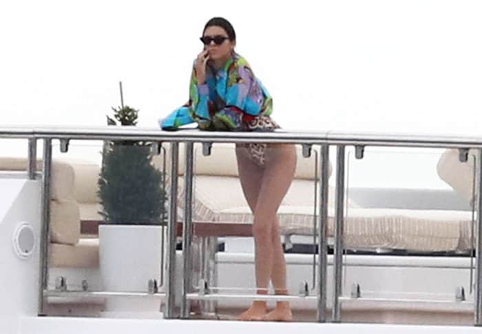 Kendall Jenner lounges on the yacht in a colorful cover-up over a leopard-print swimsuit
