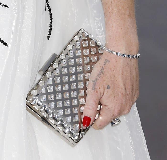 Lindsay Lohan adds a touch of sparkle to her ensemble with a studded silver clutch, a delicate diamond bracelet, and a glimpse of her hand tattoo