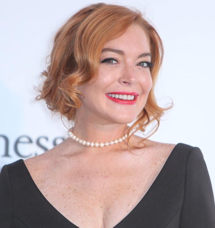 Lindsay Lohan radiates elegance with her bold red lips, classic pearl necklace, and soft, vintage-inspired curls at the 2017 amfAR Gala