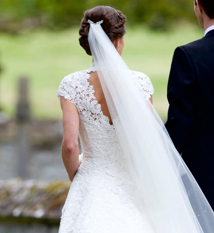 Pippa Middleton stuns in a custom Giles Deacon lace gown with an elegant open back and flowing veil as she walks hand in hand with her new husband
