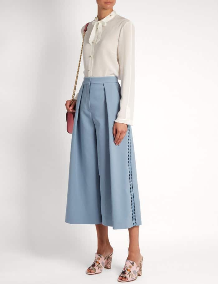 Model wearing the embroidered mules with Gucci’s high-neck ruffled blouse and Roksanda’s “Devin” trimmed crepe culottes