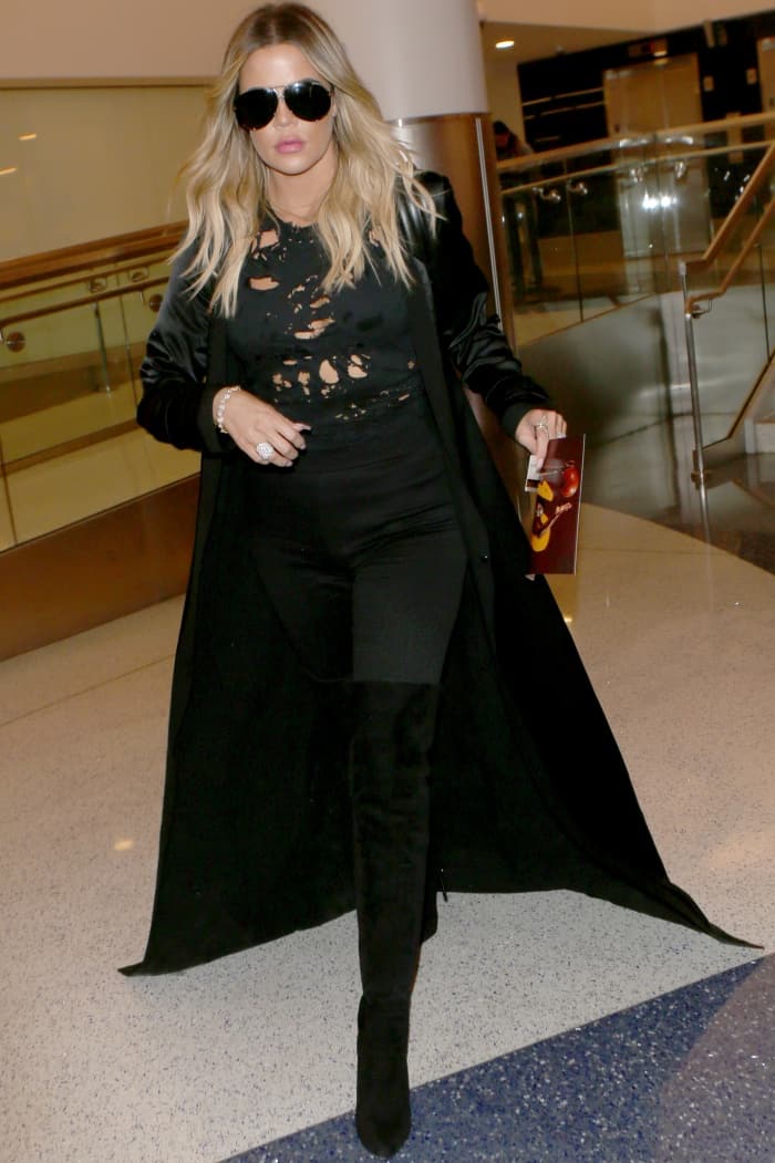 Khloe Kardashian pairs a long black coat with a distressed top and skinny jeans