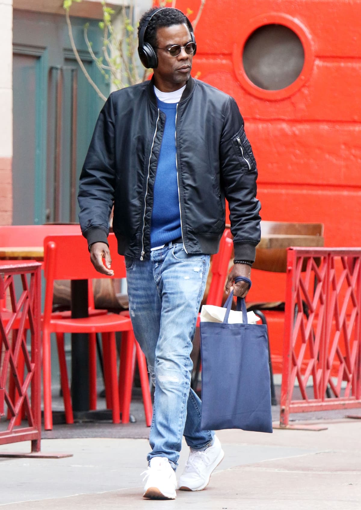 Chris Rock in jeans and white sneakers is seen listening to music