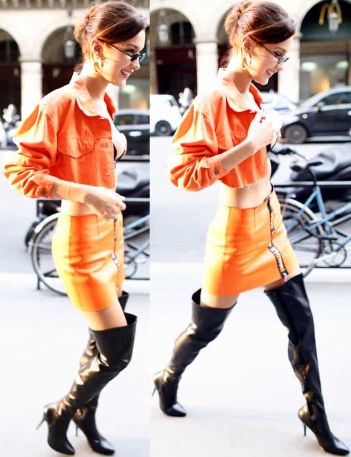 Bella Hadid wearing an orange Sami Miro jean jacket, a black bralette, an orange Heron Preston mini skirt and black patent leather thigh-high boots in Paris