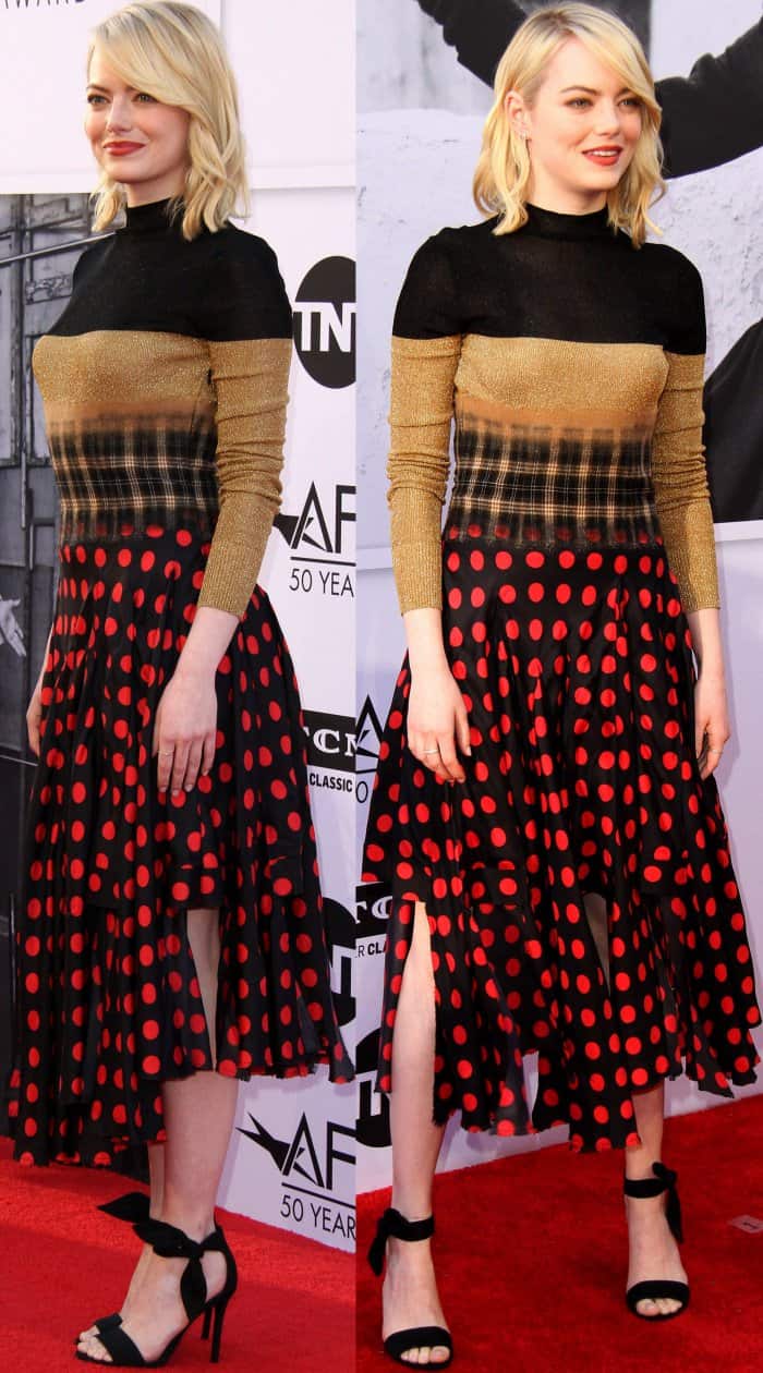 Emma Stone’s soft, side-parted waves frame her face beautifully, while her minimalist black heels and playful slit detail on her polka-dot skirt add just the right amount of elegance and flirtiness to her bold ensemble