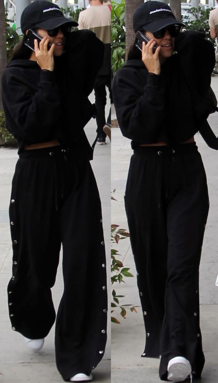 Kourtney Kardashian wearing an all-black ensemble styled with white sneakers