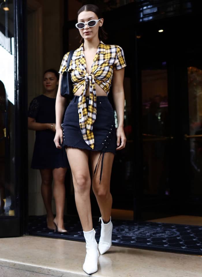 Bella Hadid in an I.am.gia top and denim skirt and Stuart Weitzman white "Clingy" booties