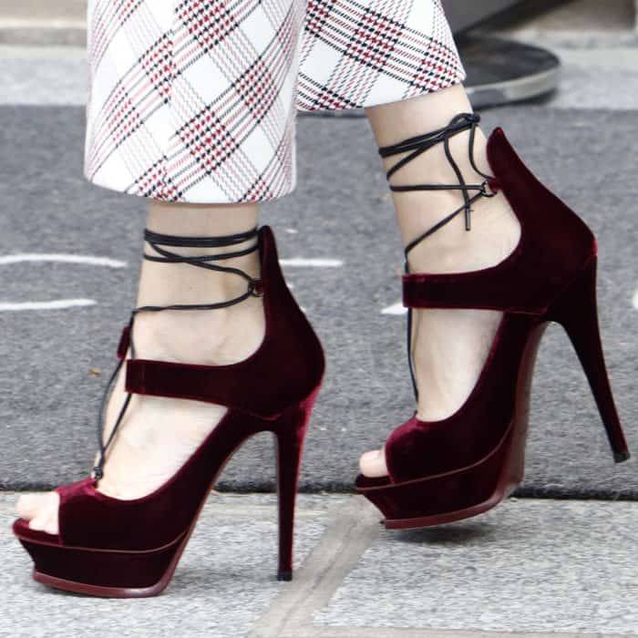 Celine Dion likely chose these bold marsala velvet Saint Laurent platform heels to add a luxurious, eye-catching touch that perfectly complements her plaid ensemble