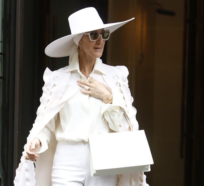 Celine Dion carries a white Celine Medium Clasp Tote during Paris Fashion Week.