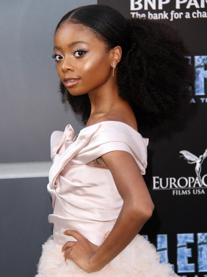 Skai Jackson exudes elegance in a soft pink, off-the-shoulder Marchesa Notte dress, complementing her look with a natural, voluminous hairstyle and subtle jewelry