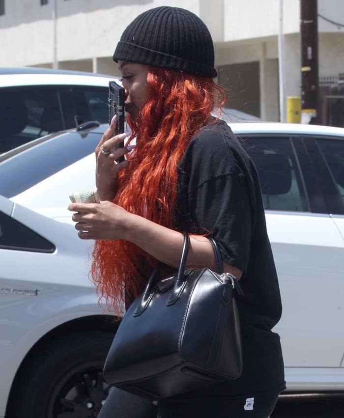 Blac Chyna carrying a black Givenchy purse and a crisp $10 bill