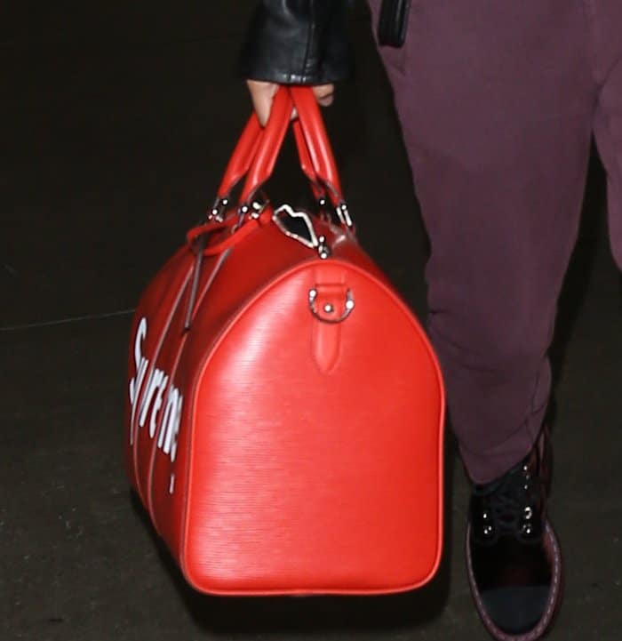 Hailey Baldwin carrying a red Louis Vuitton Supreme Keepall Bandouliere bag at the airport