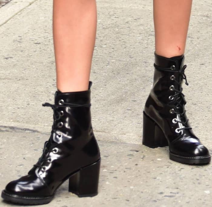 Millie Bobby Brown's choice of Stuart Weitzman's 'Climbing' ankle boots adds a sleek finish to her outfit, featuring a lace-up design and wrapped block heels for a touch of elegance